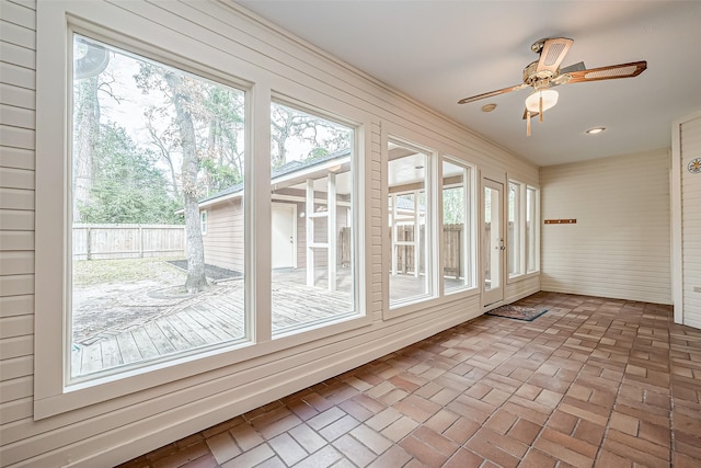 unfurnished sunroom with ceiling fan