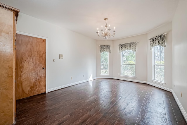 empty room featuring dark wood-type flooring and a chandelier