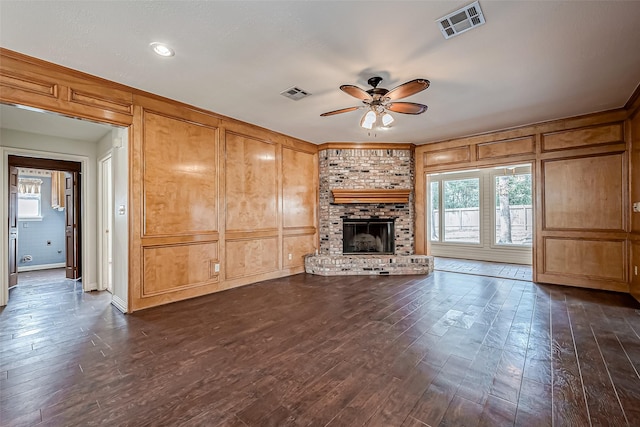 unfurnished living room featuring dark wood-type flooring, ceiling fan, a fireplace, and crown molding