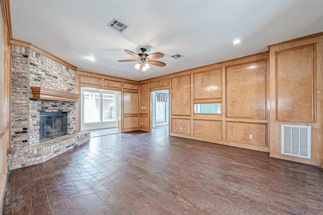 unfurnished living room with a brick fireplace, dark hardwood / wood-style floors, and ceiling fan