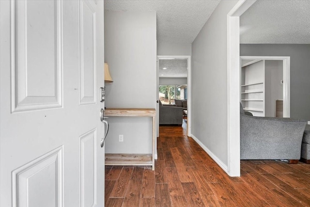 hall featuring dark wood-type flooring and a textured ceiling