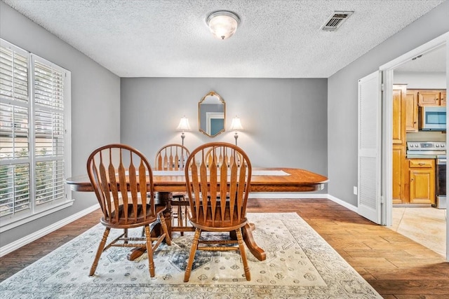 dining space featuring a textured ceiling and light hardwood / wood-style floors