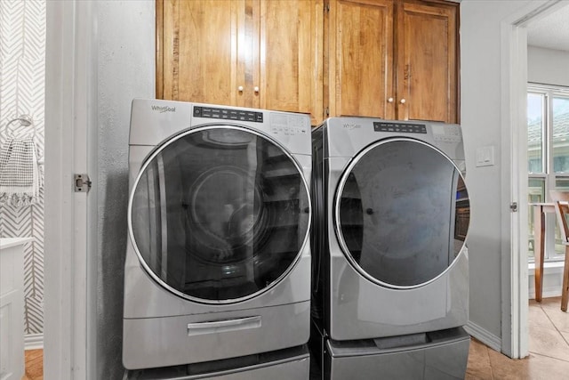 laundry room with cabinets, light tile patterned floors, and washing machine and clothes dryer