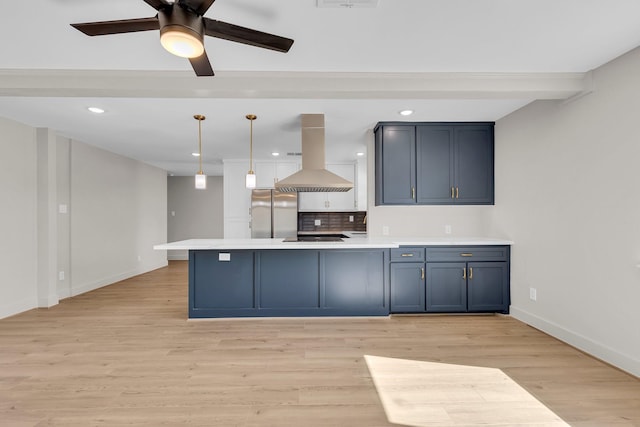 kitchen with island range hood, light countertops, freestanding refrigerator, light wood finished floors, and pendant lighting