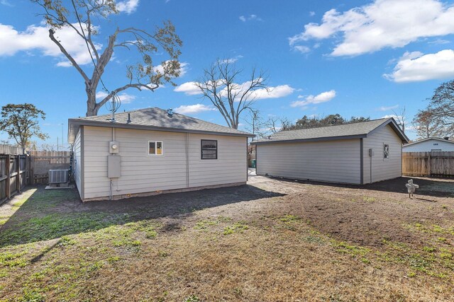 back of house featuring cooling unit, a lawn, and an outdoor structure