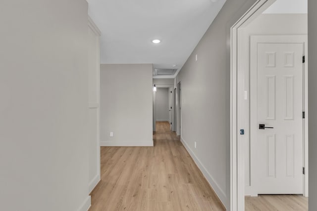 hall featuring attic access, light wood-style flooring, and baseboards