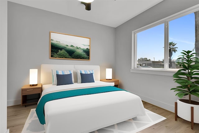 bedroom with a ceiling fan, baseboards, and light wood finished floors