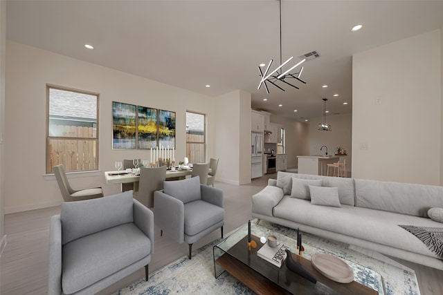 living room featuring a notable chandelier, light hardwood / wood-style flooring, and sink