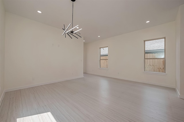 unfurnished room featuring a notable chandelier and light wood-type flooring