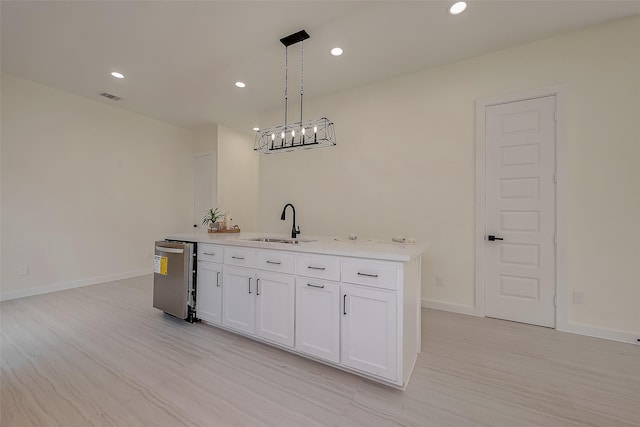 kitchen with white cabinetry, sink, pendant lighting, and light wood-type flooring