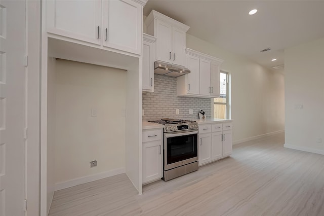 kitchen with tasteful backsplash, gas stove, white cabinets, and light hardwood / wood-style floors