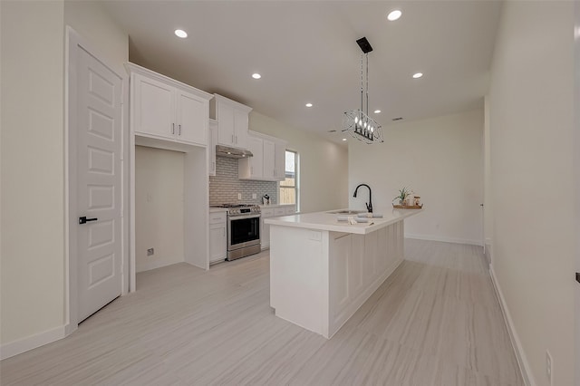 kitchen with sink, gas stove, white cabinetry, hanging light fixtures, and an island with sink