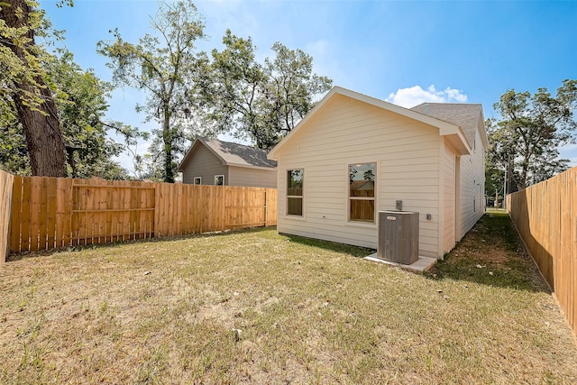 back of property with central AC and a lawn