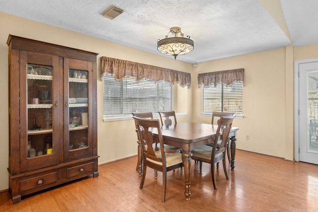 dining room featuring a textured ceiling and light wood-type flooring