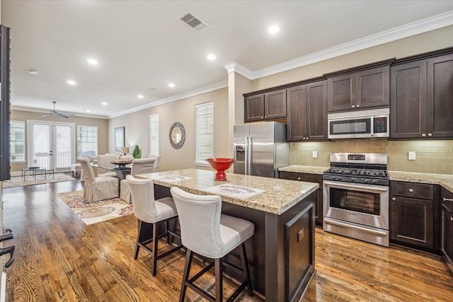 kitchen featuring light stone counters, stainless steel appliances, a center island, and a kitchen bar