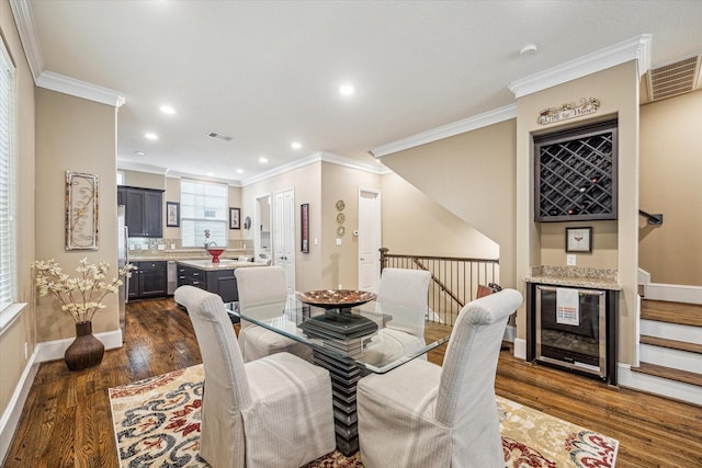 dining area featuring ornamental molding, beverage cooler, dark hardwood / wood-style flooring, and bar area