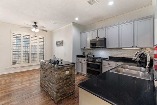 kitchen featuring sink, appliances with stainless steel finishes, gray cabinetry, dark hardwood / wood-style floors, and decorative backsplash