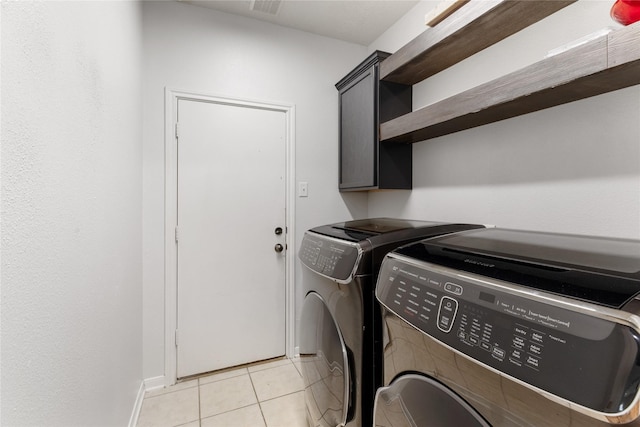 laundry room with light tile patterned floors, washing machine and dryer, and cabinets