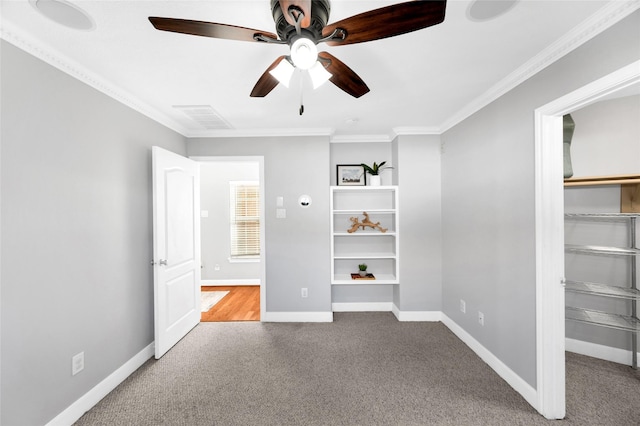 unfurnished bedroom with crown molding, a walk in closet, and carpet flooring