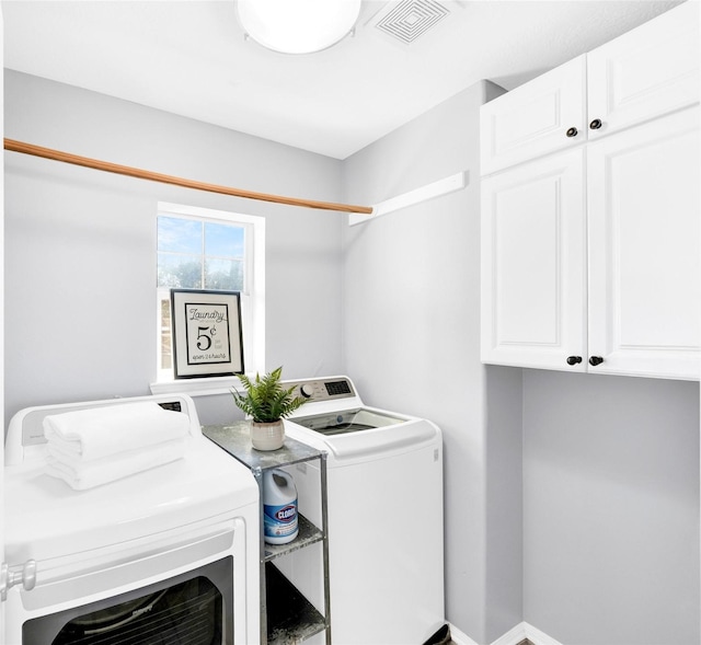 clothes washing area with cabinets and washing machine and clothes dryer