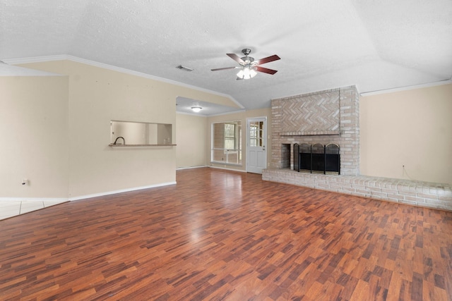 unfurnished living room with lofted ceiling, crown molding, hardwood / wood-style floors, a textured ceiling, and a brick fireplace