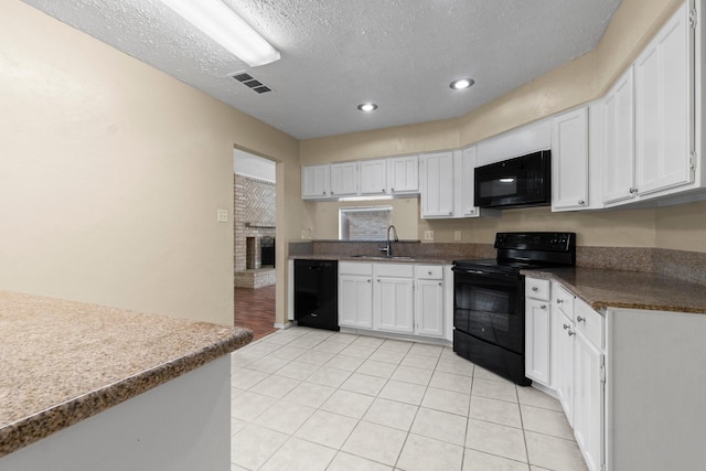 kitchen featuring sink, white cabinets, light tile patterned floors, black appliances, and a textured ceiling