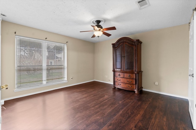 spare room with a textured ceiling, dark wood-type flooring, and ceiling fan