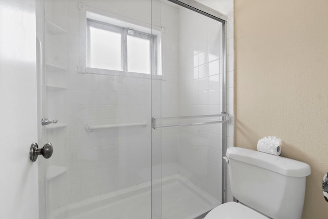 bathroom with a shower with shower door and toilet