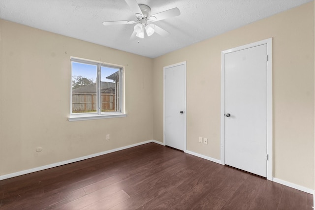 unfurnished bedroom with dark hardwood / wood-style flooring, ceiling fan, and a textured ceiling