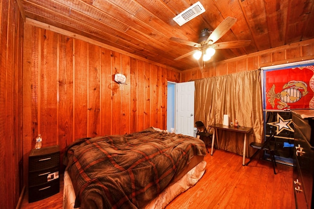 bedroom with visible vents, a ceiling fan, wood finished floors, wooden walls, and wooden ceiling