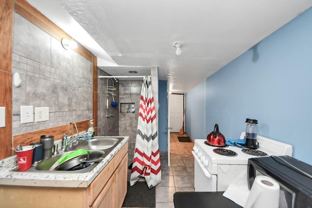 bathroom featuring tile patterned flooring, a tile shower, and a sink