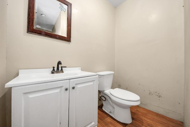 half bathroom featuring toilet, wood finished floors, and vanity