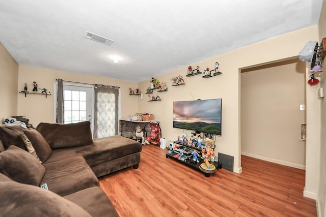 living area with wood finished floors, visible vents, and baseboards