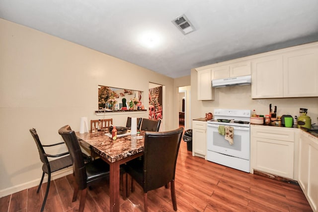 kitchen with visible vents, light wood-style flooring, electric stove, under cabinet range hood, and white cabinetry