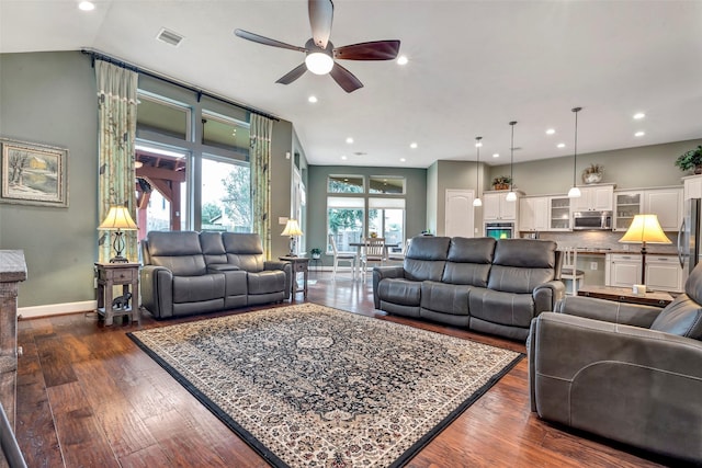 living room with ceiling fan, dark hardwood / wood-style flooring, and vaulted ceiling