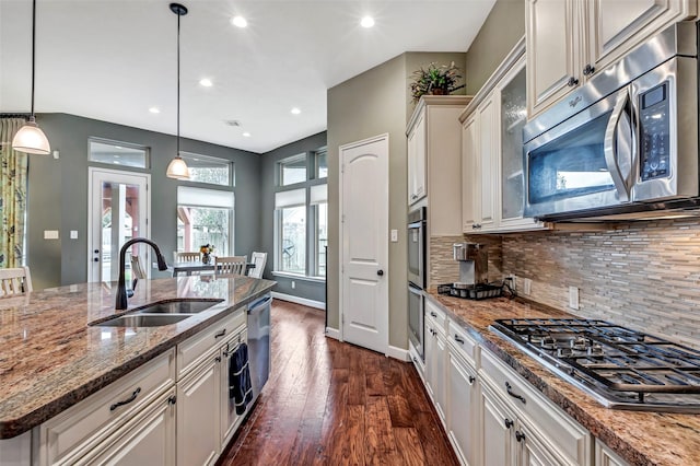 kitchen featuring stainless steel appliances, stone countertops, hanging light fixtures, and sink