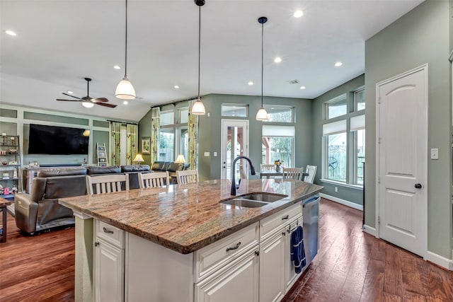 kitchen featuring sink, light stone countertops, an island with sink, and white cabinets