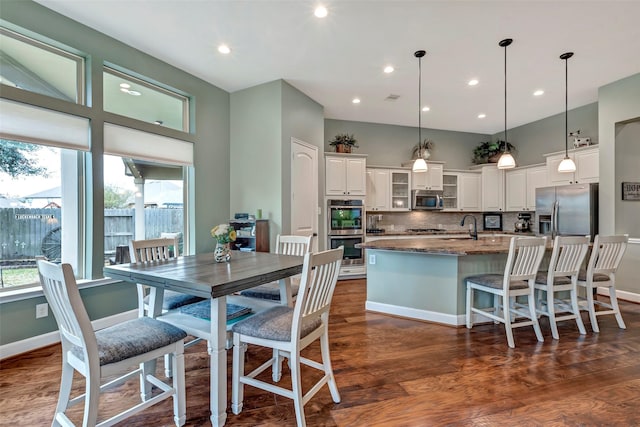 kitchen featuring dark stone countertops, an island with sink, pendant lighting, stainless steel appliances, and white cabinets