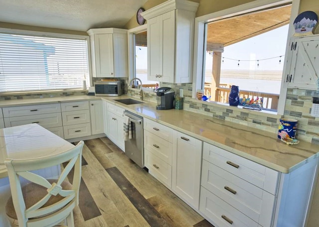 kitchen featuring sink, tasteful backsplash, stainless steel appliances, hardwood / wood-style floors, and white cabinets