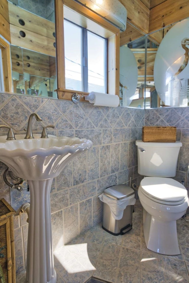 bathroom featuring tasteful backsplash, tile walls, and toilet