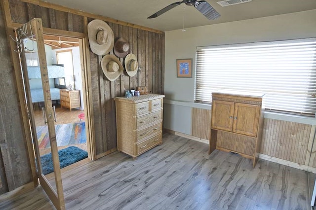 interior space featuring ceiling fan, wooden walls, and light hardwood / wood-style flooring