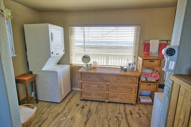 washroom featuring stacked washer and clothes dryer and light hardwood / wood-style flooring