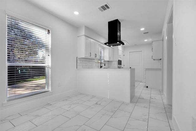 kitchen with sink, white cabinetry, tasteful backsplash, island range hood, and kitchen peninsula