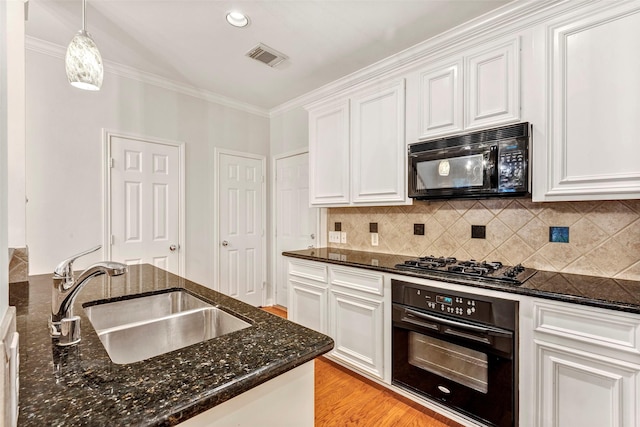 kitchen featuring sink, dark stone countertops, white cabinets, hanging light fixtures, and black appliances