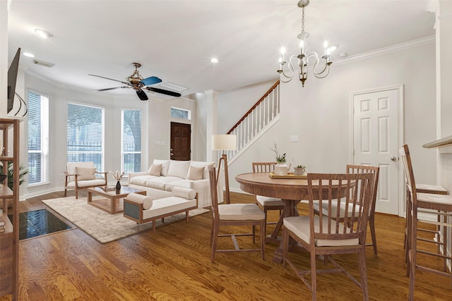 dining space featuring ornate columns, ornamental molding, ceiling fan with notable chandelier, and hardwood / wood-style floors