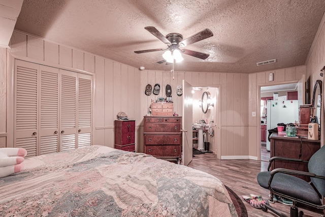 bedroom featuring ceiling fan, a textured ceiling, light wood-type flooring, and a closet