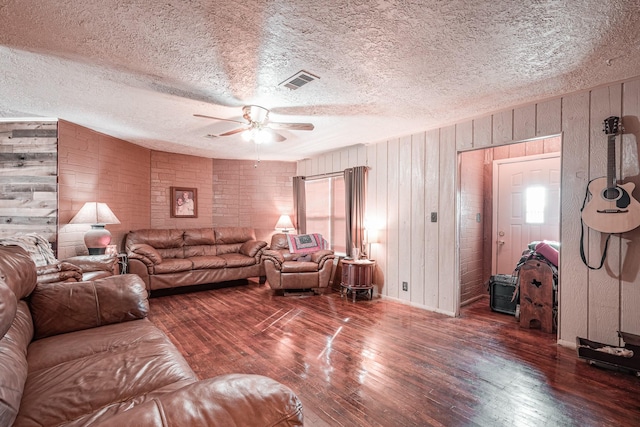 living room with ceiling fan, a textured ceiling, dark hardwood / wood-style floors, and a healthy amount of sunlight