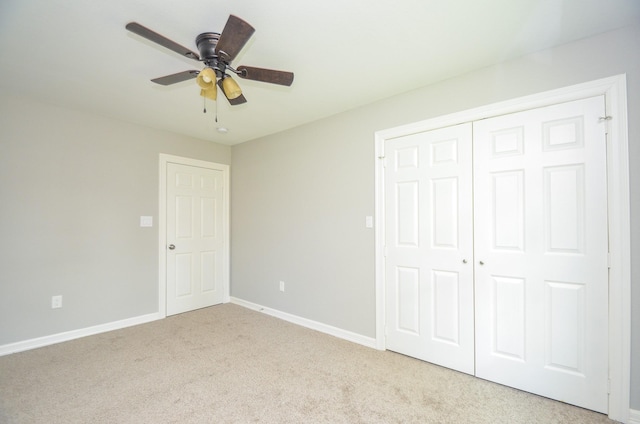 unfurnished bedroom featuring ceiling fan, a closet, and light carpet