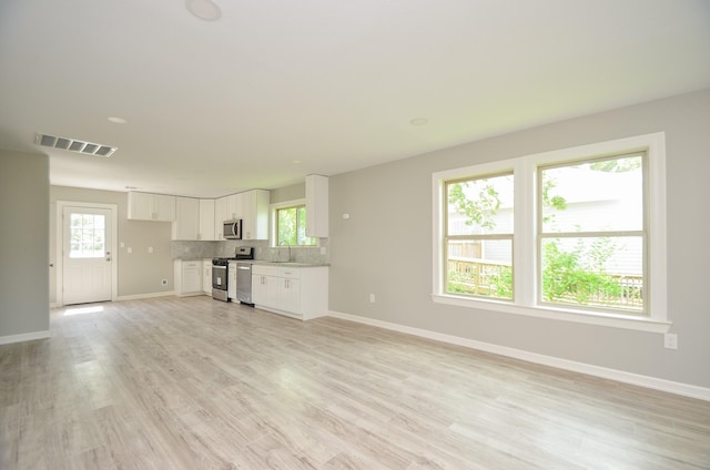 unfurnished living room featuring plenty of natural light, sink, and light wood-type flooring