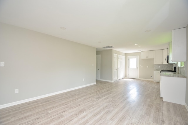 unfurnished living room featuring sink and light wood-type flooring